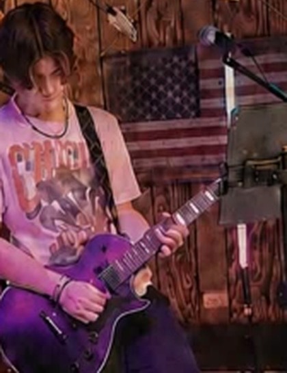 Duncan focused on stage playing a purple electric guitar
